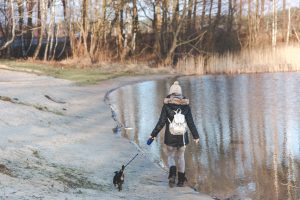 Woman and puppy on walk by lake